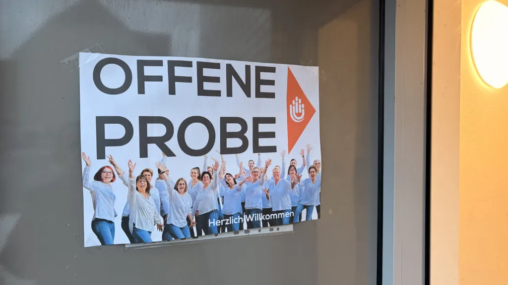 Plakat zur offenen Chorprobe des JungerChor TakeFour in Ludwigshafen. Abgebildet ist der Chor in weißen Hemden mit der Aufschrift Offene Probe – Herzlich Willkommen. Das Bild lädt alle Interessierten ein, bei der Chorprobe mitzusingen oder zuzuhören